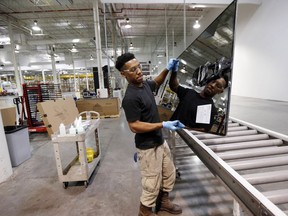 FILE- In this June 15, 2016, photo, Ricky Foster gingerly carries a completed solar panel to a shipping case after inspecting and cleaning its surface at Stion, a solar panel maker in Hattiesburg, Miss. On Thursday, Feb. 15, 2018, the Federal Reserve reports on U.S. industrial production for January.