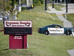 FILE- In this Feb. 15, 2018, file photo, Law enforcement officers block off the entrance to Marjory Stoneman Douglas High School, in Parkland, Fla., a deadly shooting at the school. A large Wall Street money manager wants to engage with major weapons manufacturers about their response to the school massacre in Parkland.
