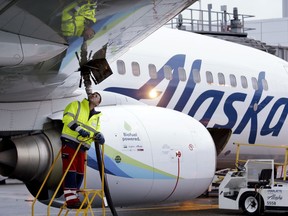 FILE - In this Nov. 14, 2016, file photo, fueling manager Jarid Svraka looks on as he fuels an Alaska Airlines Boeing 737-800 jet at Seattle-Tacoma International Airport in SeaTac, Wash. A coalition of airlines including Alaska, JetBlue and Southwest is suing Washington state over its new sick leave law, saying the measure will increase costs and delays for travelers.