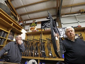 FILE--In this file photo taken Oct. 20, 2017, sales clerk Tom Wallitner holds up a Mossberg 715T .22-caliber semi-automatic rifle during an auction at Johnny's Auction House in Rochester, Wash. When selling weapons, sheriff's offices and police departments have also sold AR-15s, AK47s and other assault weapons, a practice criticized by some law enforcement officials.