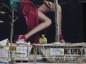A worker takes a break outside a store under construction in Madrid, Spain, Tuesday, Feb. 20, 2018.