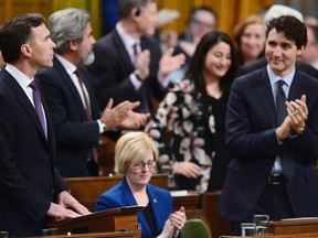 Finance Minister Bill Morneau, left, receives an ovation after delivering the federal budget in the House of Commons in Ottawa on Tuesday, Feb.27, 2018.
