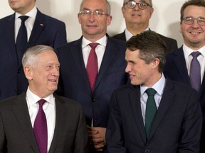 U.S. Secretary for Defense Jim Mattis, front left, speaks with British Defense Minister Gavin Williamson, front right, during a group photo of NATO defense ministers at NATO headquarters in Brussels on Wednesday, Feb. 14, 2018.