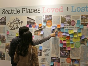 In this Dec. 15, 2017, photo, visitors to the Vanishing Seattle pop-up store in Pike Place Market in Seattle view a display where people are encouraged to post notes about places and traditions from the past that they miss about present-day Seattle. The city's booming tech industry has brought a massive influx of construction and new residents to Seattle, but backlash has been swift from those worried that the boom will change the character of single-family neighborhoods that dominate the picturesque Northwest city.
