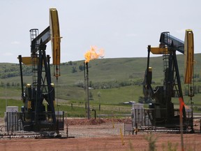 FILE -In this June 12, 2014 file photo, oil pumps and natural gas burn off in Watford City, N.D. The Interior Department says it is replacing an Obama-era regulation aimed at restricting harmful methane emissions from oil and gas production on federal lands. A rule being published in the Federal Register this week will replace the 2016 rule with requirements similar to those that were in force before the Obama administration changed the regulation.