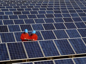 FILE - In this Feb. 7, 2012, file photo, workers check solar panels at a solar power station on a factory roof in Changxing in eastern China's Zhejiang province. One of China's biggest makers of solar panels said Tuesday, Feb. 6, 2018, that it will invest $309 million to expand manufacturing in India to guard against what it said is a rising threat of import controls in the United States and other markets. (Chinatopix via AP, File)
