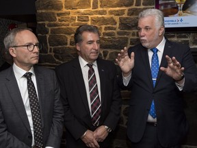 Minister of Public Security Martin Coiteux, MNA for Jean-Lesage Andre Drolet and Quebec Premier Philippe Couillard talk to the press in a Quebec City pub on Wednesday February 21, 2018. Calling Quebec's liquor laws incredibly complicated, Public Security Minister Martin Coiteux said Wednesday new legislation will simplify the lives of alcohol consumers and sellers.Bill 170 allows parents with kids to remain on a patio until 11 p.m. instead of 8 p.m., gives tourists the right to take a beer bought at the hotel bar back to their room, and liberates businesses open for a few months a year from having to buy a full-year alcohol permit.