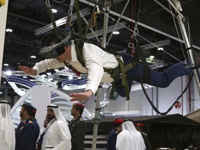 A visitor to a drone conference tries out a parachute simulator in Abu Dhabi, United Arab Emirates, Sunday, Feb. 25, 2018. The United Arab Emirates on Sunday opened a stand-alone trade show featuring military drones called the Unmanned Systems Exhibition & Conference, showing the power the weapons have across the Middle East.