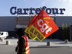 An employees of French retail giant Carrefour Group protests job cuts outside a Carrefour hypermarket, in Aix-en-Provence, southern France, Thursday Feb. 8, 2018. Carrefour CEO Alexandre Bompard announced last month cost savings of 2 billion euros (2.44 billion US dollars) by 2020. CGT union stands for General Working Confederation.
