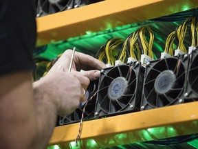 An employee changes the fan on a mining machine at the Bitfarms cryptocurrency farming facility in Farnham, Quebec.