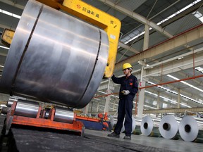 A Chinese worker checks aluminum tapes at an aluminum production plant in Huaibei, east China's Anhui province.