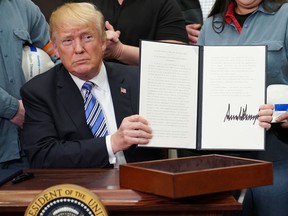 U.S. President Donald Trump shows his signature on Section 232 Proclamations on Steel and Aluminum Imports in the Oval Office of the White House on March 8, 2018.
