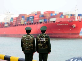 Chinese police officers watch a cargo ship at a port in Qingdao in China's eastern Shandong province on March 8, 2018.