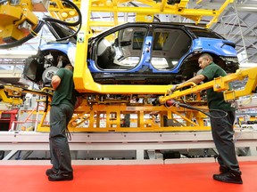 Employees work on a Range Rover Sport SUV using robotic arms at Tata Motors Ltd.'s Jaguar Land Rover vehicle manufacturing plant in Solihull, U.K.