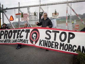 Environmentalist David Suzuki, centre, stops briefly to pose with protesters at an entrance to Kinder Morgan in Burnaby, B.C.