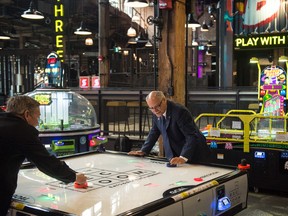 Cineplex CEO Ellis Jacob (right) takes on an opponent in air hockey in a Rec Room location.