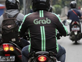 FILE - In this Monday, July 24, 2017, file photo, a GrabBike driver rides on his motorbike in Jakarta, Indonesia. The Southeast Asian ride hailing app Grab is expanding into financial services in partnership with a Japanese credit card company, hoping to offer credit to millions of people without bank accounts.