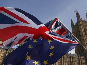Demonstrators fly a Union flag and an EU flag outside of the Houses of Parliament in Westminster, central London on Oct. 12, 2017