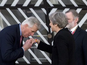 FILE - In this Friday, March 23, 2018 file photo, European Union chief Brexit negotiator Michel Barnier, left, kisses the hand of British Prime Minister Theresa May as they arrive for an EU summit in Brussels.  Thursday March 29, 2018, marks 365 days until Britain leaves the European Union, ending a 46-year marriage that has entwined the economies, legal systems and peoples of Britain and 27 other European nations.