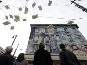 Avital Food Tours culinary guide Philip Hall, obscured, speaks to a group taking the tour about a mural atop a restaurant in San Francisco.