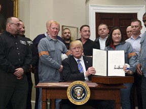 President Donald Trump holds up a proclamation on steel imports during an event in the Roosevelt at the White House in Washington, Thursday, March 8, 2018. He also signed one for aluminum imports.