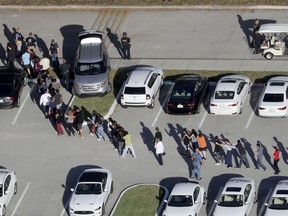 FILE - In this Feb. 14, 2018, file photo, students are evacuated by police from Marjory Stoneman Douglas High School in Parkland, Fla., after a shooter opened fire on the campus. Modern technology has enabled real-time reaction, support and calls for action during deadly mass shootings in the U.S. Live video of the Florida shooting showed survivors under desks while others live-tweeted messages to the survivors.