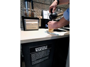 FILE -In In this Sept. 22, 2017, file photo, a customer pours milk into coffee near a posted Proposition 65 warning sign at a Starbucks coffee shop in Los Angeles. Superior Court Judge Elihu Berle has ruled that California law requires coffee companies to carry an ominous cancer warning label because of a chemical produced in the roasting process. Judge Berle wrote in a proposed ruling Wednesday, March 28, 2018, that Starbucks and other coffee companies failed to show that the threat from a chemical compound produced in the roasting process was insignificant. At the center of the dispute is acrylamide, a carcinogen found in many cooked foods, that is produced during the roasting process.