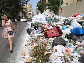 A woman holds her breath as she walks near a temporary garbage dump in Jdeideh, northeast of Beirut in 2016.