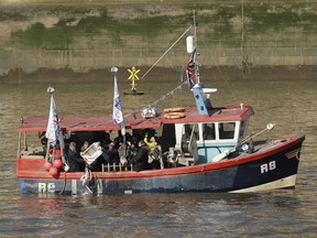 Former pro-Brexit UK Independence Party (UKIP) leader Nigel Farage, center, helps tip a container of fish into the River Thames in London, Wednesday, March 21, 2018. Farage joined fisherman to dump fish into the Thames Wednesday, in a protest stunt against the proposals for how Britain's fishing industry will be affected the Brexit transition deal with the EU.