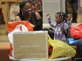 FILE- In this Dec. 21, 2017, file photo, Mercedes Amos, left, and her daughter Jhene Rivers, 2, right, of Orangeburg, S.C., rest after a day of holiday shopping at Concord Mills mall in Concord, N.C. On Tuesday, March 27, 2018, the Conference Board releases its March index on U.S. consumer confidence.