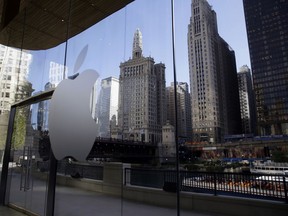 In this Oct. 19, 2017, photo, downtown buildings and a tour boat are reflected on the mirror behind an Apple logo during a preview event at an Apple Michigan Avenue store in downtown Chicago. Apple plans to hold at an education-focused event at Lane Technical College Prep High School in Chicago on Tuesday, March 27, 2018.