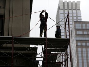FILE- In this Feb. 20, 2018, file photo, construction workers work in midtown Manhattan in New York. On Wednesday, March 7, the Labor Department issues revised data on productivity in the four quarter.