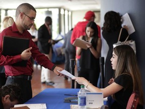 In this Tuesday, Jan. 30, 2018 photo, an employee of Aldi, right, takes an application from a job applicant at a JobNewsUSA job fair in Miami Lakes, Fla. On Wednesday, March 7, 2018, payroll processor ADP reports how many jobs private employers added in February.