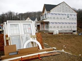 FILE- In this Feb. 16, 2018, file photo, building materials are stacked along home sites as construction is under way at a new housing plan in Zelienople, Pa. On Friday, March 16, 2018, the Commerce Department reports on U.S. home construction in February.