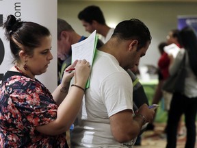 In this Jan. 30, 2018 photo, Loredana Gonzalez, of Doral, Fla., fills out a job application at a JobNewsUSA job fair in Miami Lakes, Fla. On Friday, March 9, 2018, the Labor Department reports on job openings and labor turnover for January.