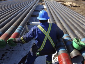 Oil field worker Fred Iron moves production pipe at an oil pad at the Devon Jackfish facility site, in Conklin, Canada.