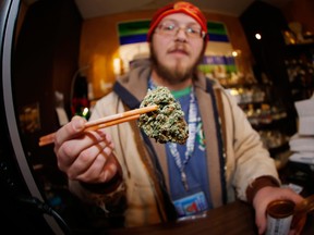 An employee at a marijuana dispensary in Denver holds up a bud for a customer. Recreational sale of marijuana has been legal here since January 2014.