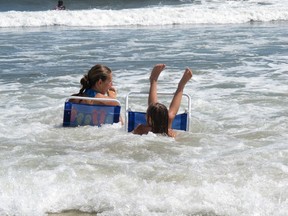In this Aug. 28, 2012 photo, Christine Sroka of Morrisville Pa., left, looks on as a wave knocks over her 7-year-old daughter Julia, right, on the Belmar, N.J. beach. Some coastal states including New Jersey that oppose President Donald Trump's plan to allow offshore drilling in deeper federal waters along most of the nation's coastline are using state-level laws to try to make it difficult or impossible to conduct drilling in their areas by banning pipelines or other drilling infrastructure in state waters.