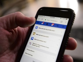 A cell phone user thumbs through the privacy settings on a Facebook account in Ottawa on Wednesday, March 21, 2018.