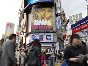 In this Feb. 11, 2018, photo, a huge advertisement of Bitcoin is displayed near Shibuya train station in Tokyo. The Japanese government is slapping penalties on several crypotocurrency exchanges in the country, after 58 billion yen ($530 million) of virtual coins were lost earlier this year from hacking. The Financial Services Agency, which has been checking the exchanges, said Thursday, March 8, 2018, that FSHO and Bit Station exchanges were ordered to halt operations for a month.