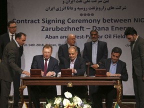 Director General of Russian state-controlled Zarubezhneft Oil Co. Sergey Kudryashov, seated left, Managing Director of the National Iranian Oil Company, NIOC, Ali Kardor, center, and CEO of Iranian private Dana Energy Co. Mohammad Iravani, sign documents for a $740 million agreement to develop two oil fields near the Iraqi border, in Tehran, Iran, Wednesday, March 14, 2018.