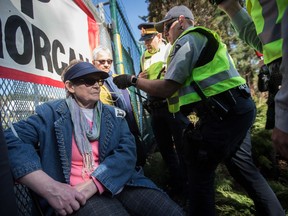 RCMP officers arrest a woman who tied herself to a gate outside Kinder Morgan in Burnaby, B.C., on Saturday March 17, 2018. Approximately 30 people who blockaded an entrance - defying a court order - were arrested while protesting the Kinder Morgan Trans Mountain pipeline expansion. The pipeline is set to increase the capacity of oil products flowing from Alberta to the B.C. coast to 890,000 barrels from 300,000 barrels.