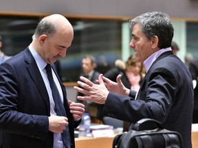 European Commissioner for Economic and Financial Affairs Pierre Moscovici, left, speaks with Greek Finance Minister Euclid Tsakalotos during a meeting of EU finance ministers at the Europa building in Brussels, Tuesday March 13, 2018.