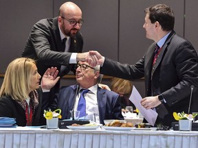 European Commission President Jean-Claude Juncker, seated, speaks with Secretary-General of the European Commission Martin Selmayr, right, as he shakes hands with Belgian Prime Minister Charles Michel during a breakfast meeting at an EU summit in Brussels on Friday, March 23, 2018. Leaders from the 28 European Union nations meet for a second day of an EU summit to assess the state of Brexit negotiations and the prospect of a trade war with the United States.