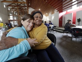 In this Monday, March 5, 2018, photo, Patrice E., right, who declined to provide her last name, embraces her friend Ronda Rohde inside a church building where they are among the two-dozen women living in their vehicles in the adjacent parking lot in Kirkland, Wash. Some of the obstacles faced by the women in finding permanent housing may soon become illegal in Washington state, where legislators are advancing a bill that would prohibit landlords from turning away tenants who rely on Section 8 vouchers, Social Security or veterans benefits.