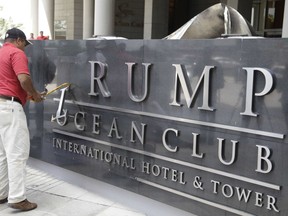 In this March 5, 2018 photo, a man removes the word Trump, off a marquee outside the Trump Ocean Club International Hotel and Tower in Panama City.  Lawyers for President Donald Trump's family hotel business threatened a Panamanian judicial official handling a dispute related to Trump Hotels' management of a 70-story luxury hotel, according to a complaint filed with the anticorruption division of Panama's chief prosecutor.