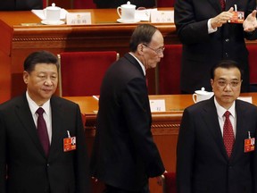 Chinese President Xi Jinping, left, and Premier Li Keqiang, right, stand as Vice President Wang Qishan arrives at the closing session of the annual National People's Congress in Beijing's Great Hall of the People in Beijing, China, Tuesday, March 20, 2018.