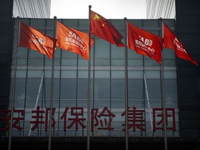 FILE - In this Feb. 23, 2018, file photo, Chinese and corporate flags fly in front of the offices of the Anbang Insurance Group in Beijing. The founder of the Chinese insurer that owns New York City's Waldorf Hotel went on trial Wednesday, March 28, 2018 on charges of fraud and abusing his position for personal benefit.