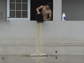 FILE - In this Sept. 27, 2017 file photo, a resident bails water from a flooded home in the aftermath of Hurricane Maria, in Catano, Puerto Rico. The storm caused an estimated $100 billion in damage, killed dozens of people and damaged or destroyed nearly 400,000 homes, according to Puerto Rico's government.