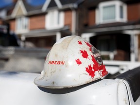Aecon Group Inc. signage is displayed on a worker's hardhat at a construction site in Toronto, Ontario.